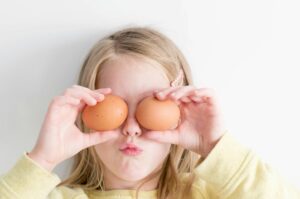 girl holding two eggs while putting it on her eyes