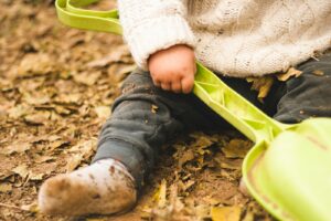 child holding green plastic shovel toy